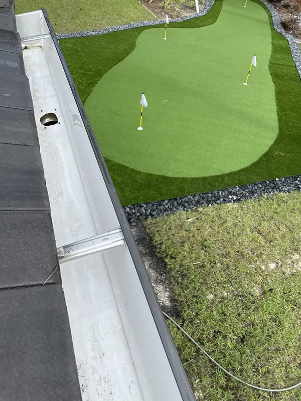 After photo of a gutter above a putting green, as cleaned by Happy Home Detailing.